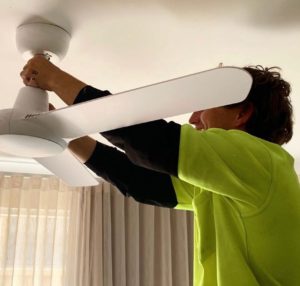 An electrician installs a ceiling fan
