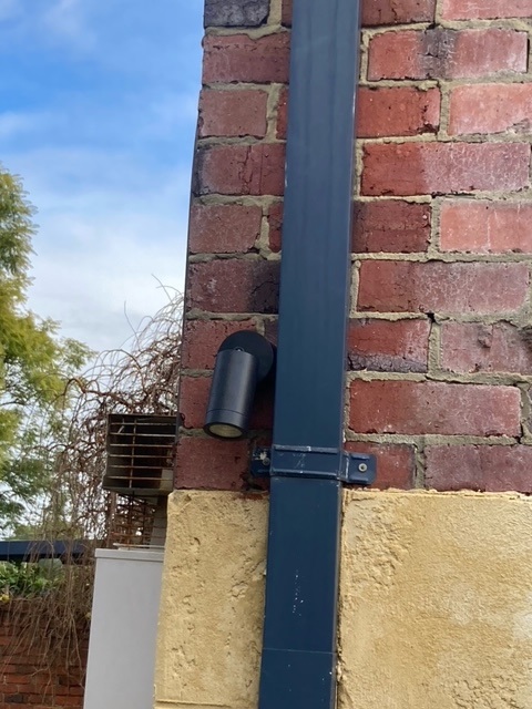 A modern light on a brick wall next to a pipe